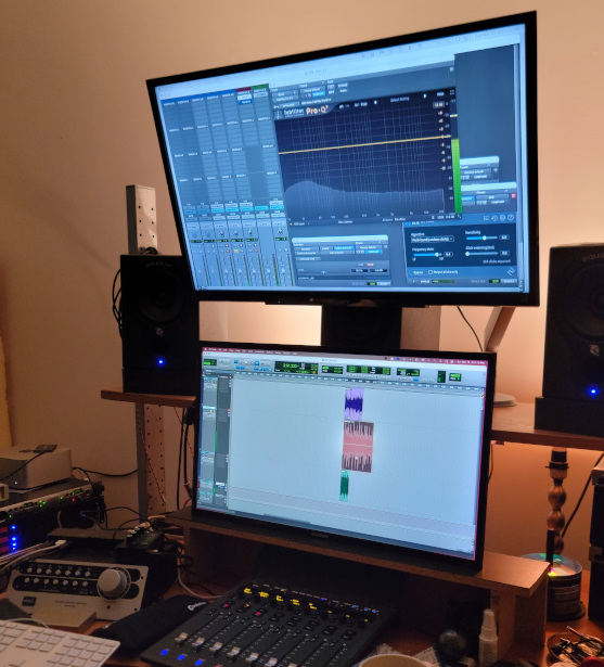 Computer screens, sound mixers, and speakers on a desk